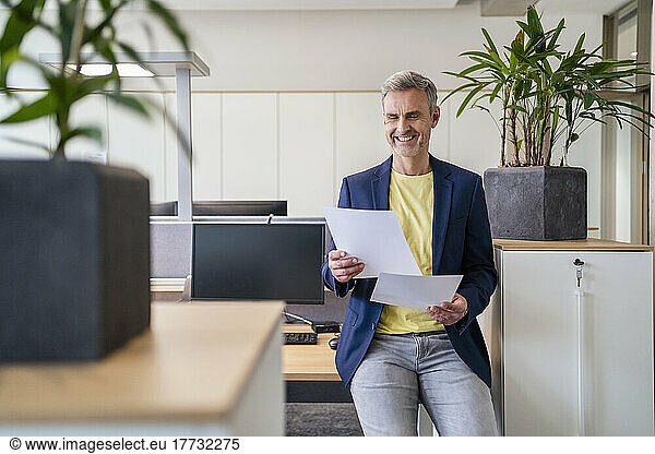 Smiling businessman working on papers in office