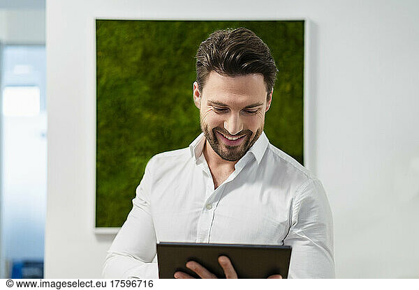 Smiling businessman working on tablet PC in office