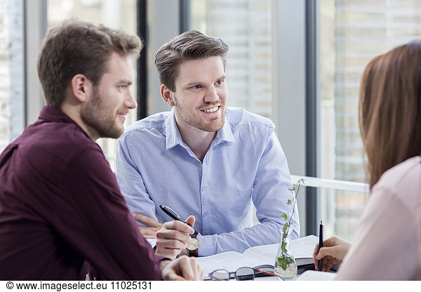 Smiling businessmen looking at female colleague in meeting