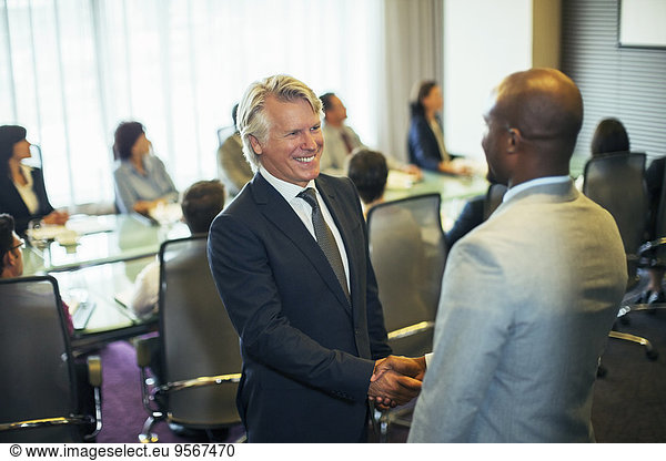 Smiling businessmen shaking hands during meeting in conference room