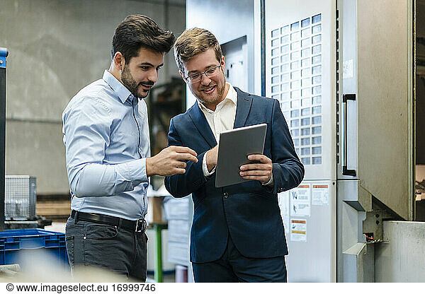 Smiling businessmen using digital tablet at industry