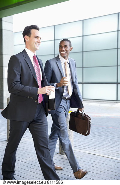 Smiling businessmen walking with coffee