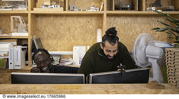 Smiling businessmen working at computers in office