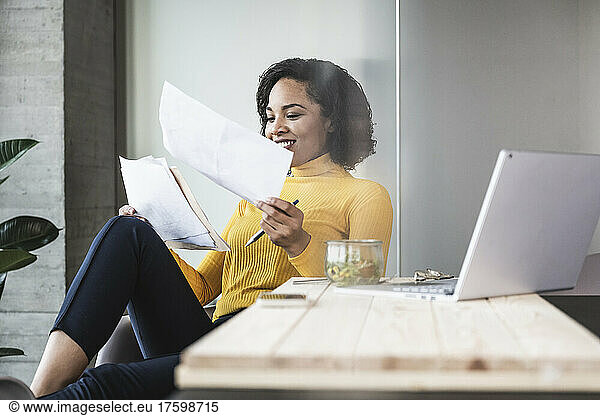 Smiling businesswoman analyzing documents in office
