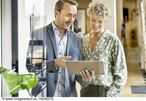 Smiling businesswoman and businessman discussing over tablet PC