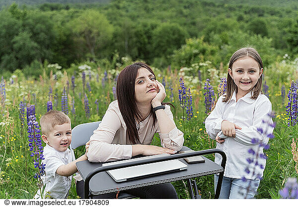 Smiling businesswoman at desk with children in meadow