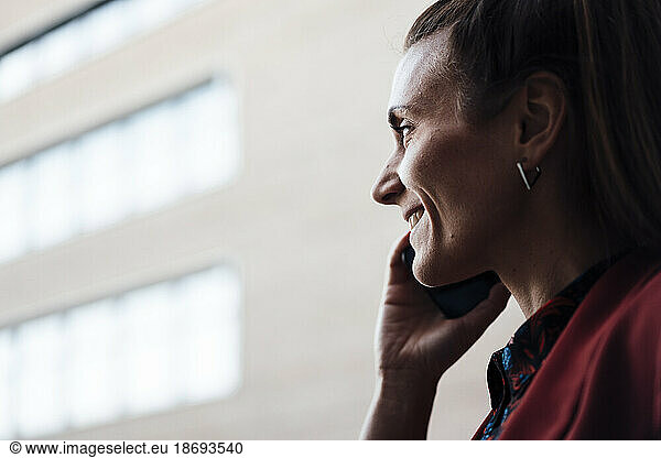 Smiling businesswoman communicating through mobile phone