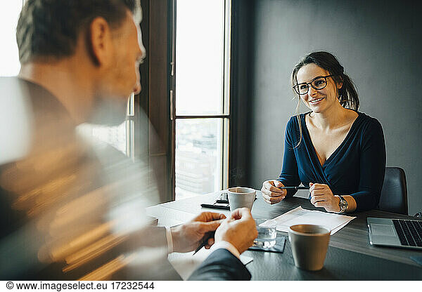 Smiling businesswoman discussing with male colleague in board room at office