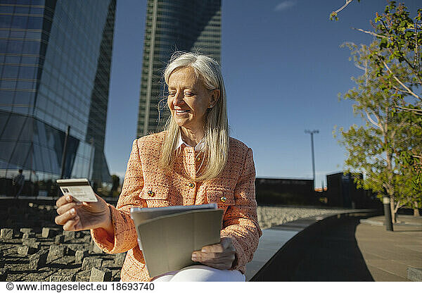 Smiling businesswoman doing online shopping holding tablet PC and credit card