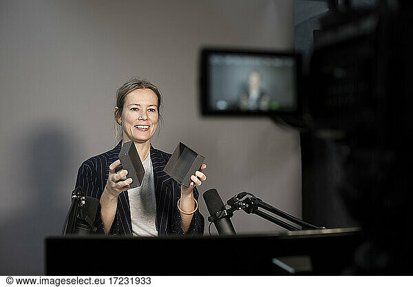 Smiling businesswoman explaining about product while recording through camera at creative office