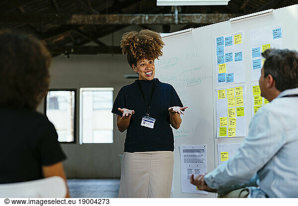 Smiling businesswoman gesturing and discussing in front of whiteboard