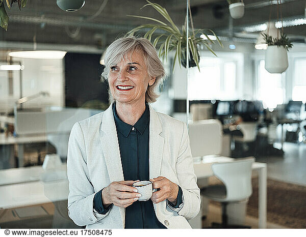 Smiling businesswoman holding coffee cup in office