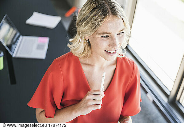 Smiling businesswoman holding digitized pen in office