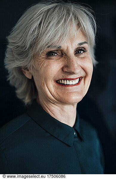 Smiling businesswoman in front of black wall