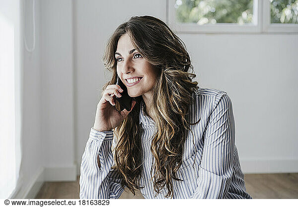 Smiling businesswoman in office using mobile phone by window