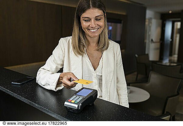 Smiling businesswoman making contactless credit card payment at restaurant