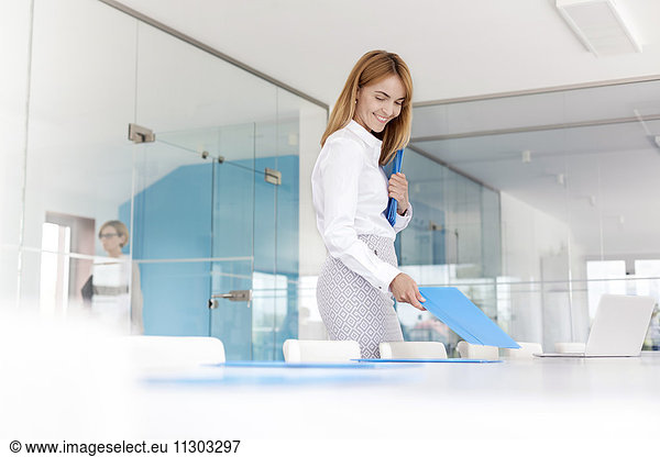 Smiling businesswoman placing folders on conference room table