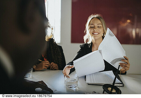 Smiling businesswoman reading agreement sitting in board room at office