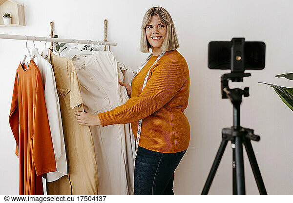 Smiling businesswoman showing dress on video call at creative office