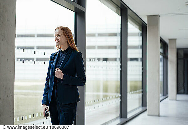 Smiling businesswoman standing near window at office