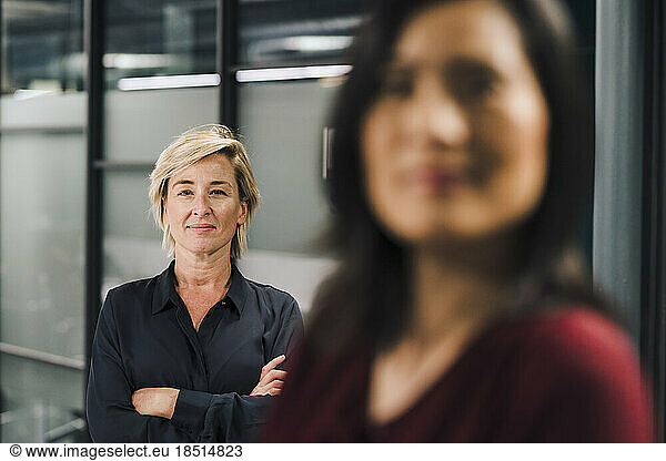 Smiling businesswoman standing with colleague in foreground