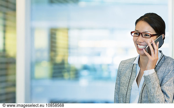 Smiling businesswoman talking on cell phone in office