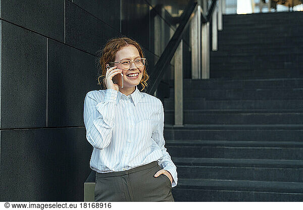 Smiling businesswoman talking on mobile phone by staircase