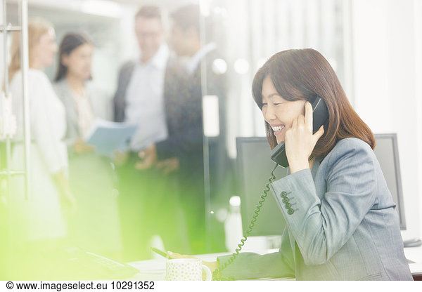 Smiling businesswoman talking on telephone in office