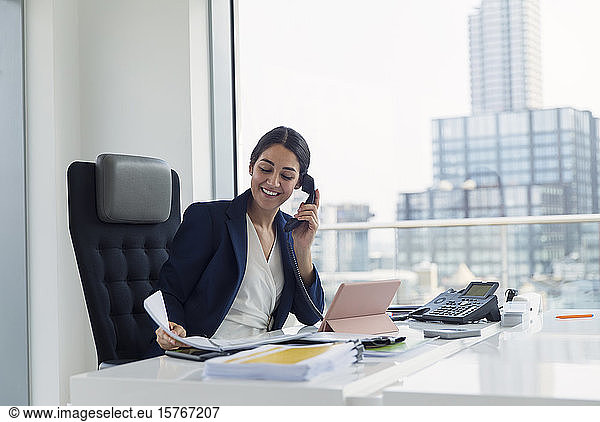 Smiling businesswoman talking on telephone in urban office