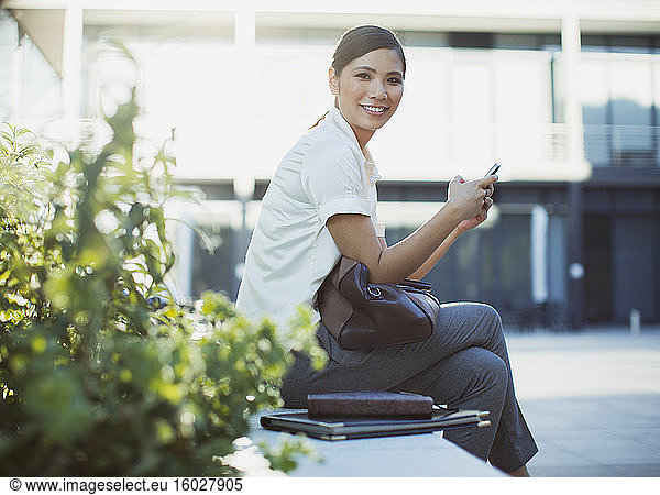 Smiling businesswoman text messaging outdoors