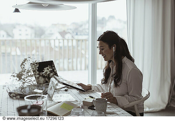 Smiling businesswoman using digital tablet at home office