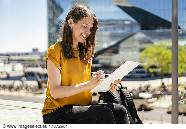 Smiling businesswoman using digitized pen on tablet PC