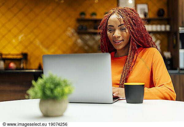 Smiling businesswoman using laptop at desk in modern office