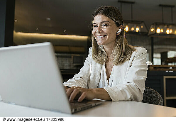 Smiling businesswoman using laptop at restaurant