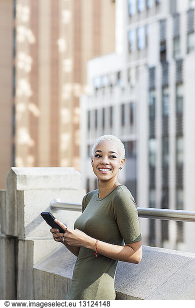 Smiling businesswoman using mobile phone in office balcony
