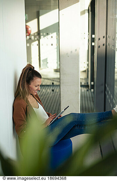 Smiling businesswoman using tablet PC sitting at office