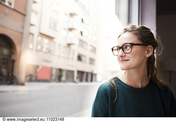 Smiling businesswoman wearing glasses while looking through office window