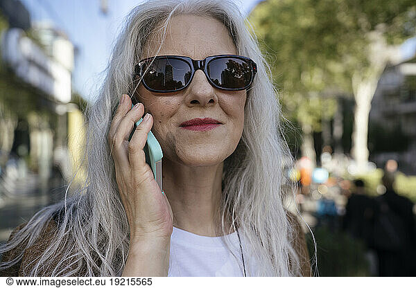 Smiling businesswoman wearing sunglasses talking on mobile phone