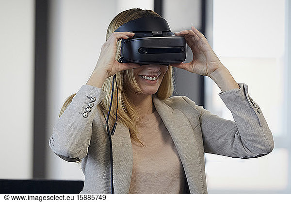 Smiling businesswoman wearing VR glasses in office