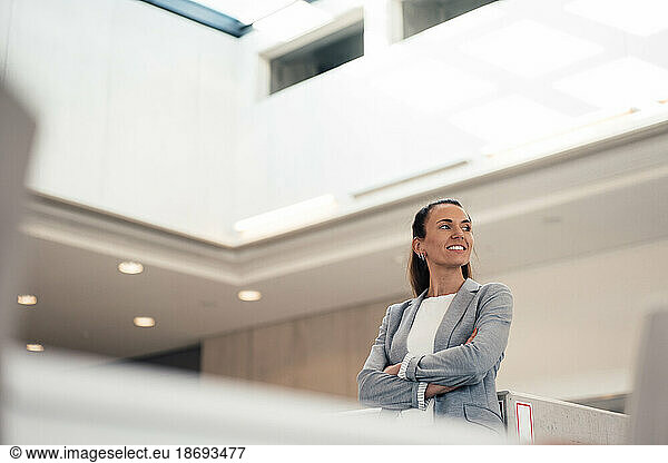 Smiling businesswoman with arms crossed at office