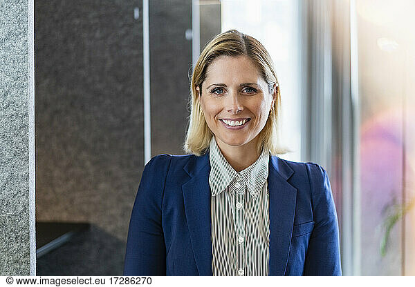Smiling businesswoman with blond hair standing in office