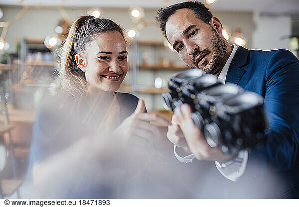 Smiling businesswoman with colleague discussing over lighting equipment