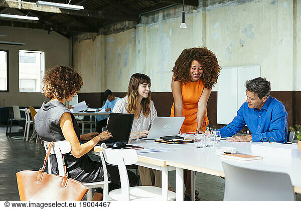 Smiling businesswoman with colleagues working at desk