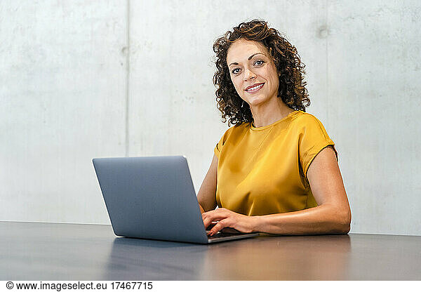 Smiling businesswoman with laptop at desk