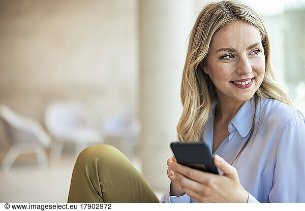 Smiling businesswoman with mobile phone in office