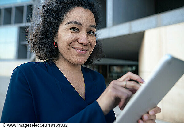 Smiling businesswoman with tablet PC at office park