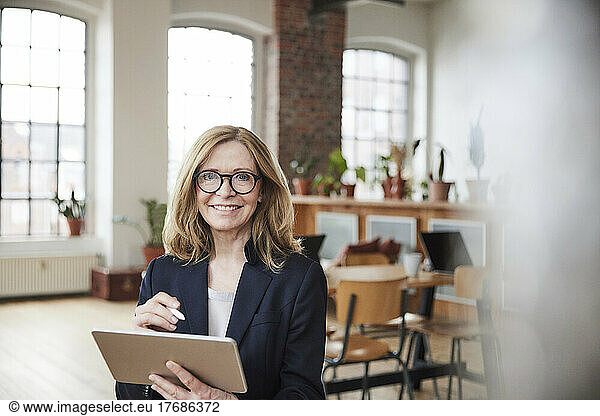 Smiling businesswoman with tablet PC working in living room at home