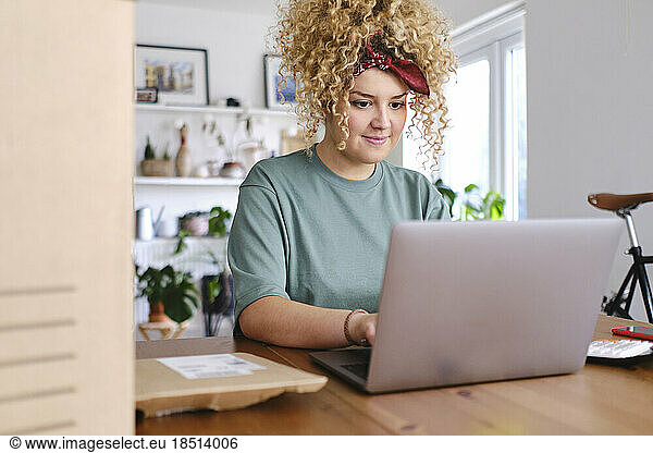 Smiling businesswoman working on laptop at desk