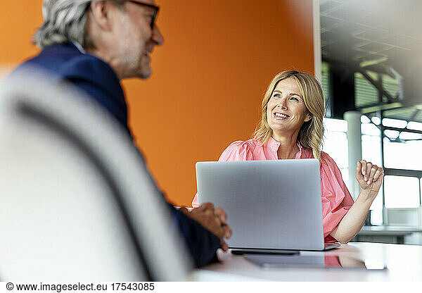 Smiling businesswoman working with colleague in office