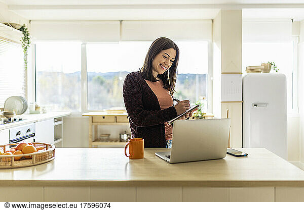 Smiling businesswoman writing in notebook working at home